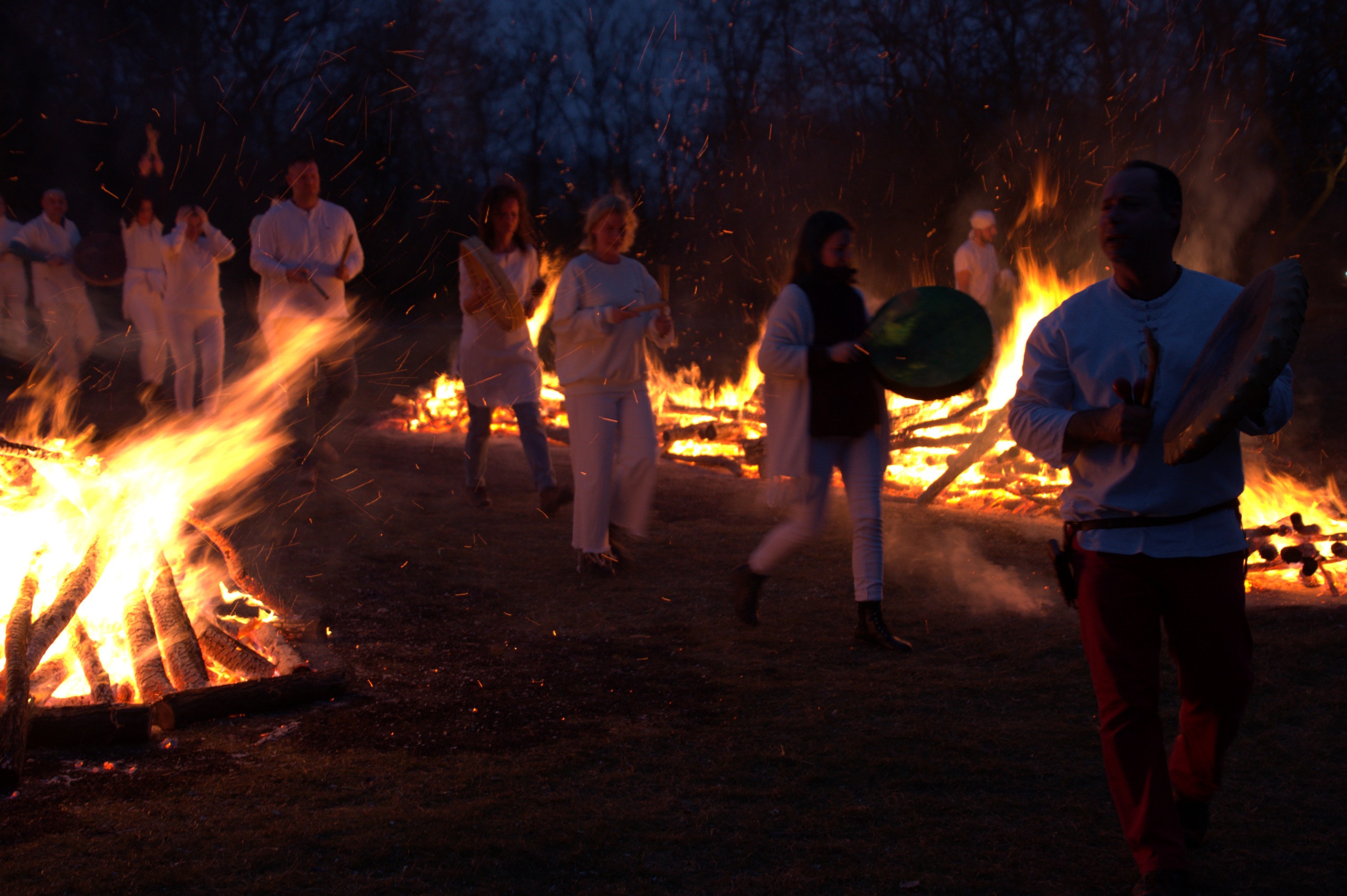 Participants carrying ceremonial drums among the fires at a Napkapu gathering