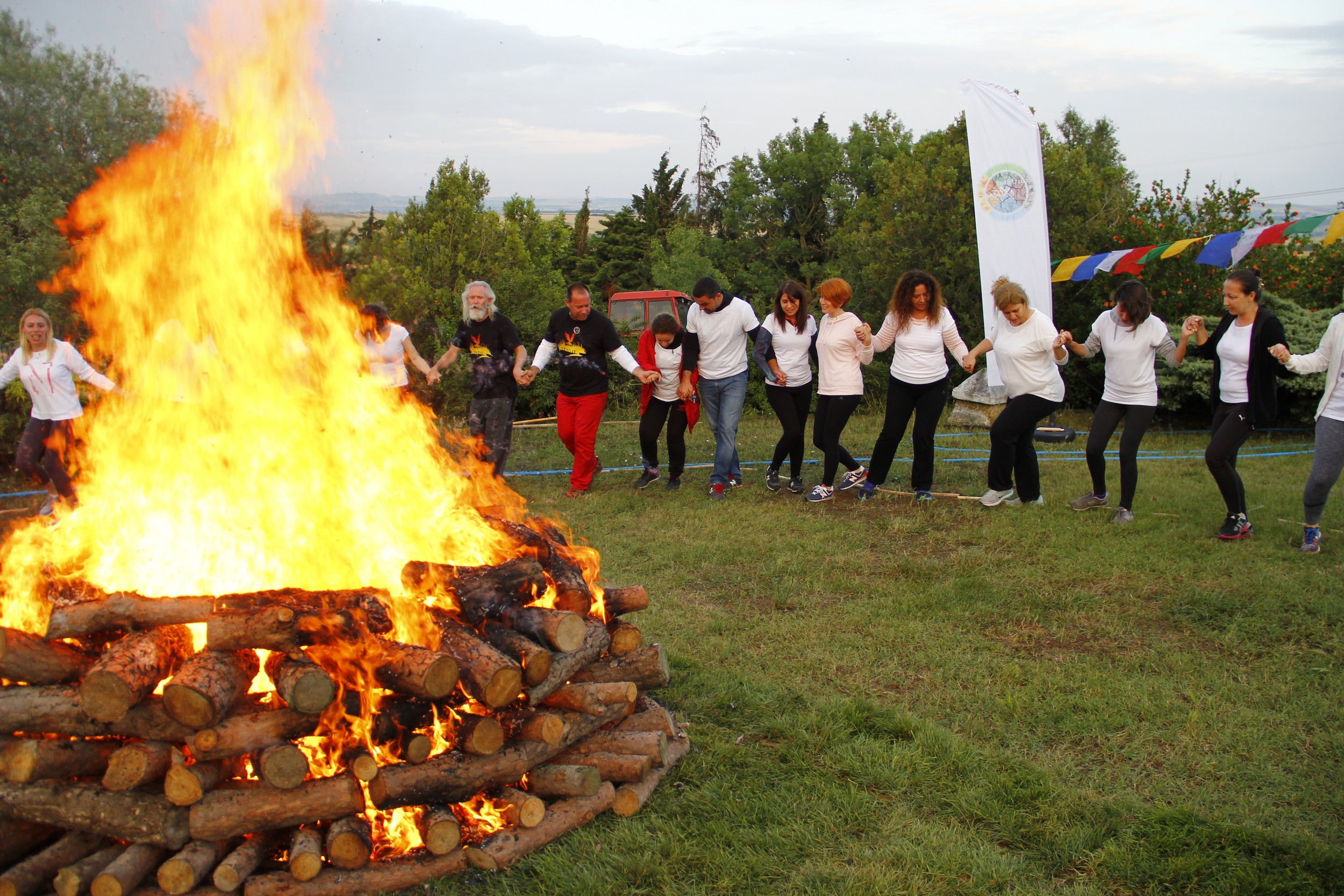 A community holding hands around a large fire