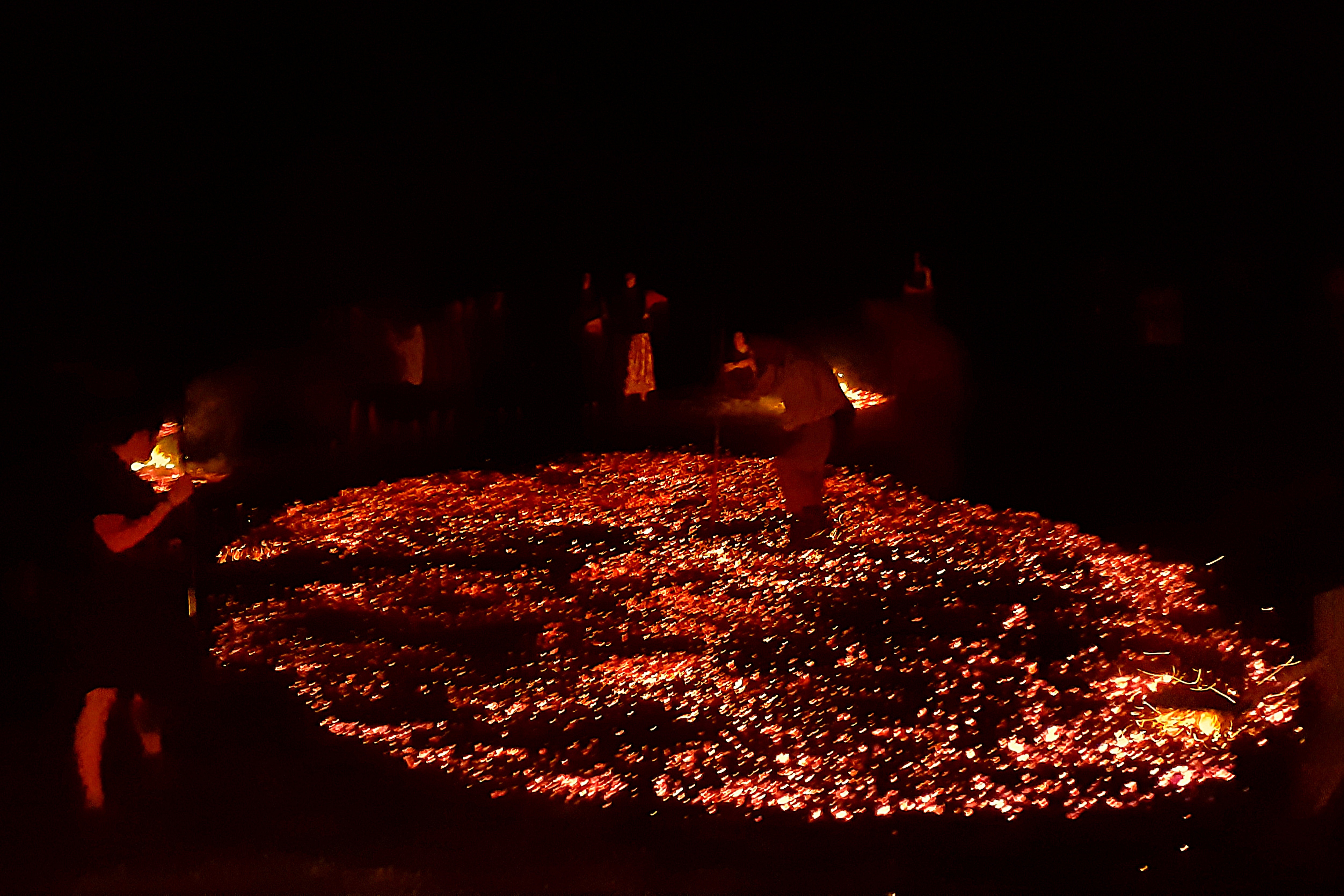 A complete circular field of glowing embers with the firekeeper tending it