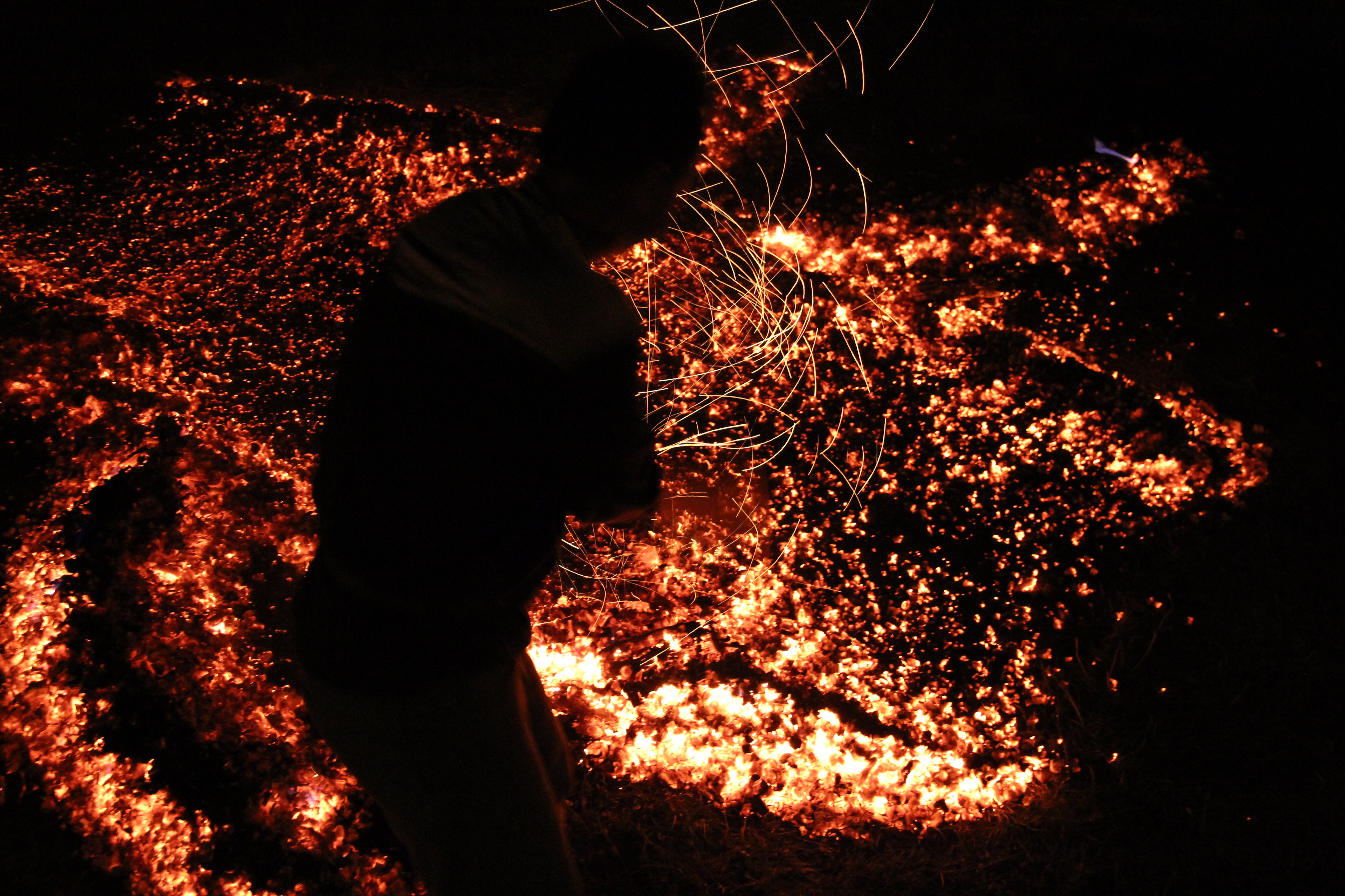 A solitary silhouette crossing glowing embers