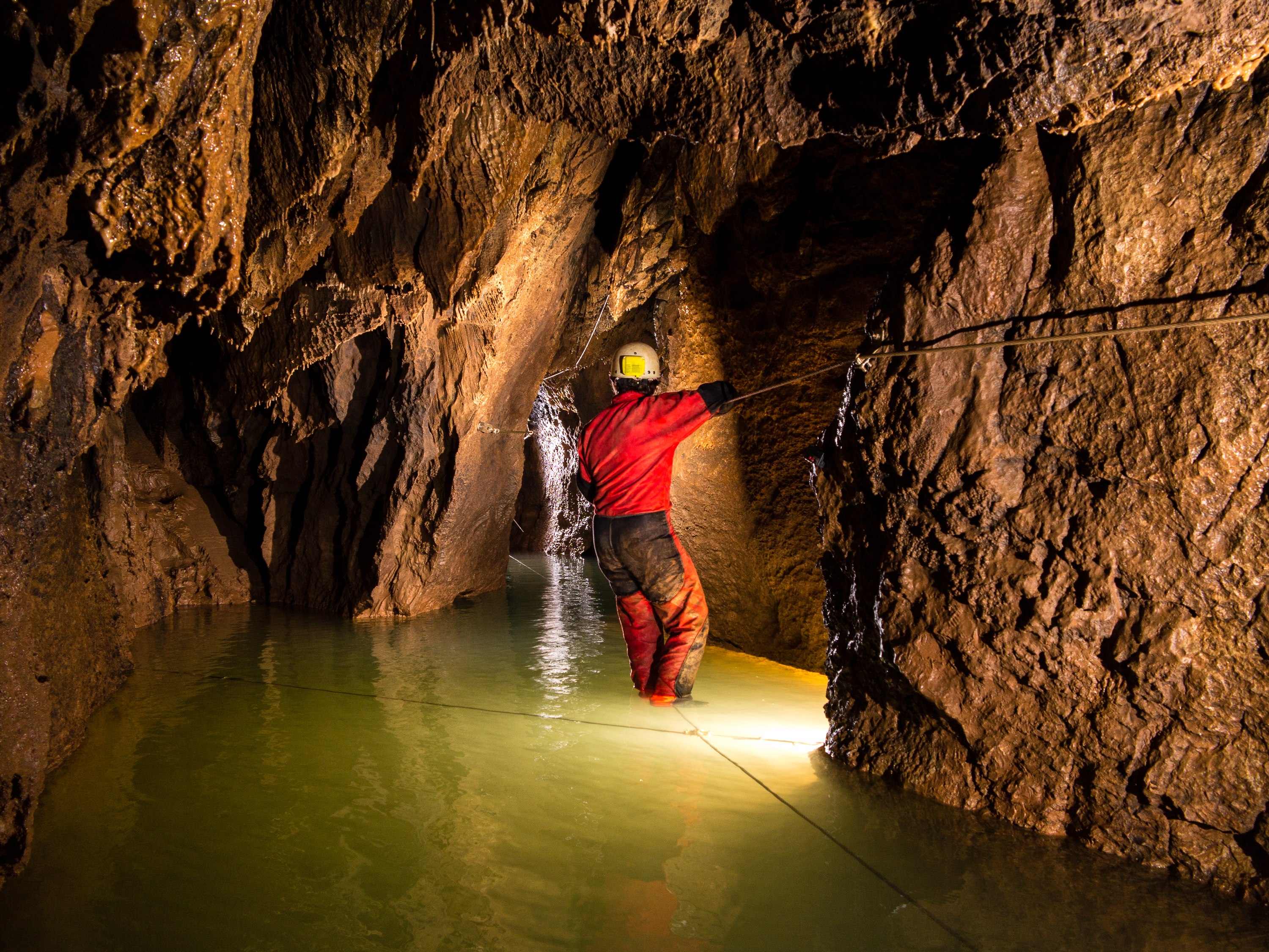 A participant exploring a stone passage inside a cave