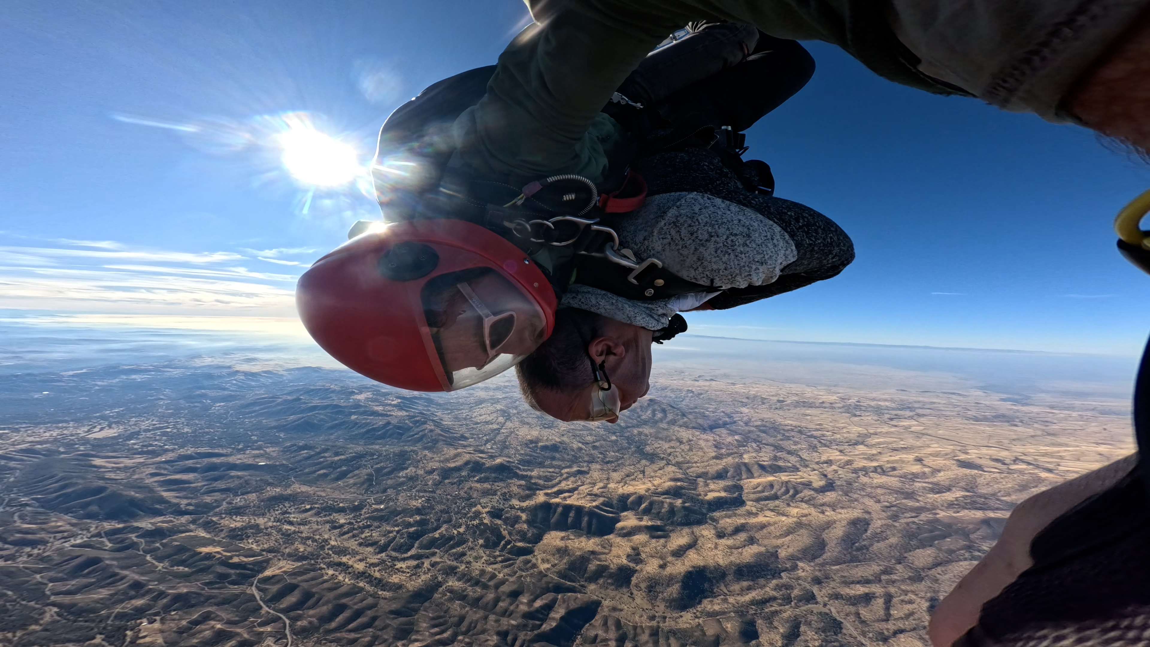 A tandem skydiver entering freefall above a vast horizon