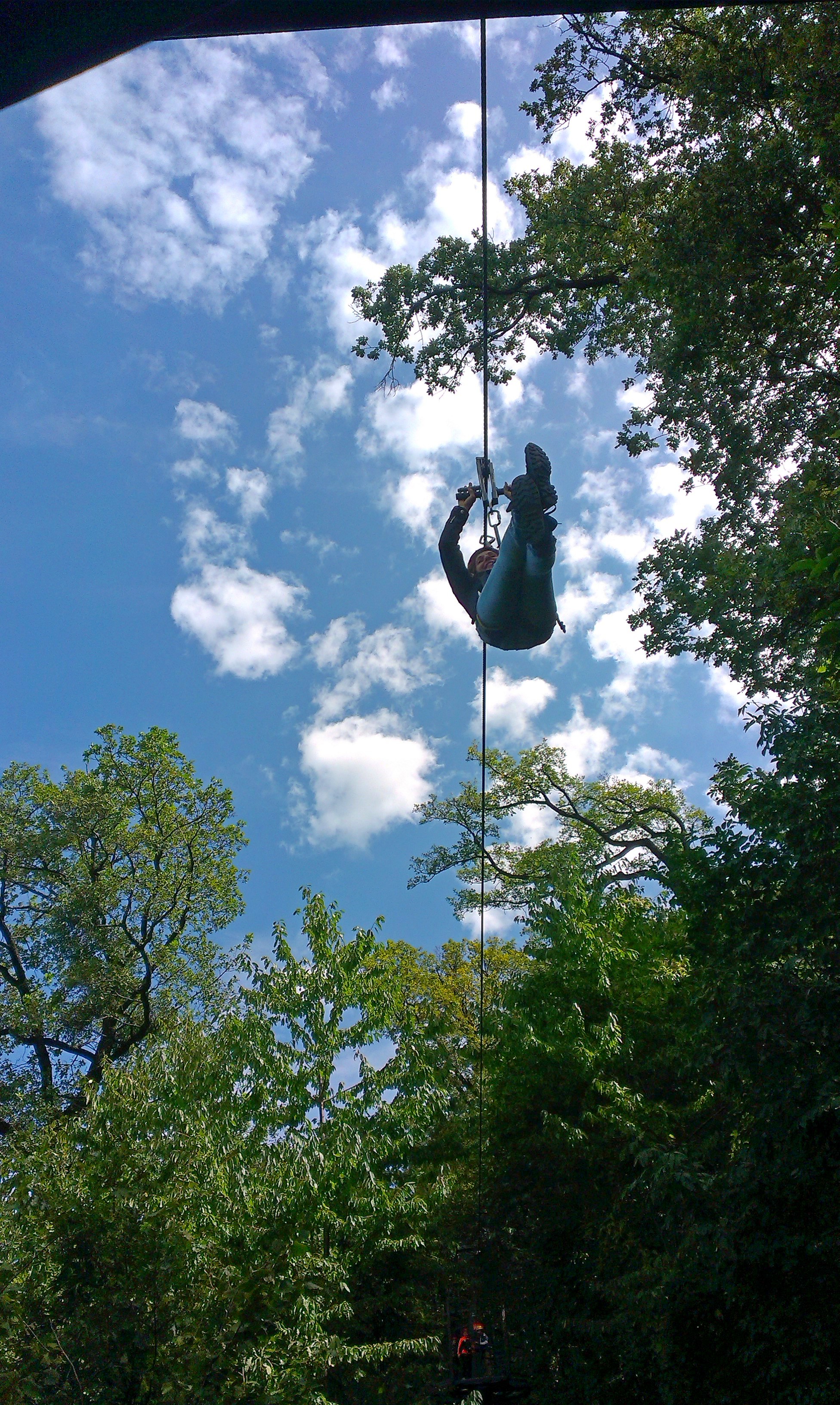 A participant ascending on a rope beneath an open sky