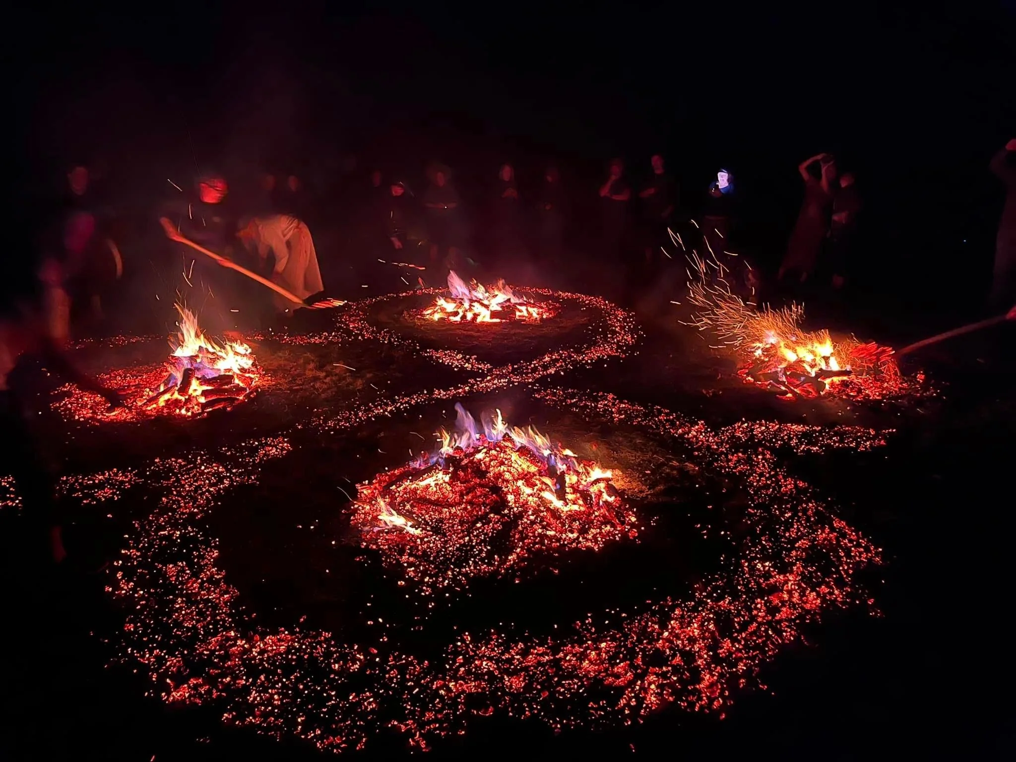Multiple glowing ember paths arranged around small fires