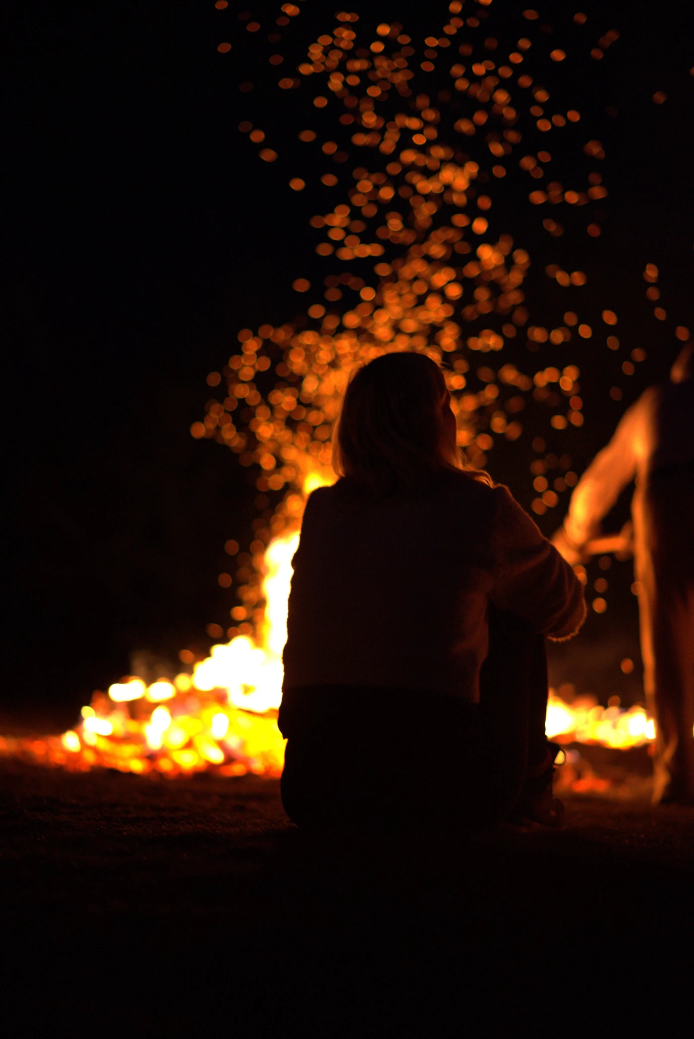A participant sitting in a self-embrace beside the fire