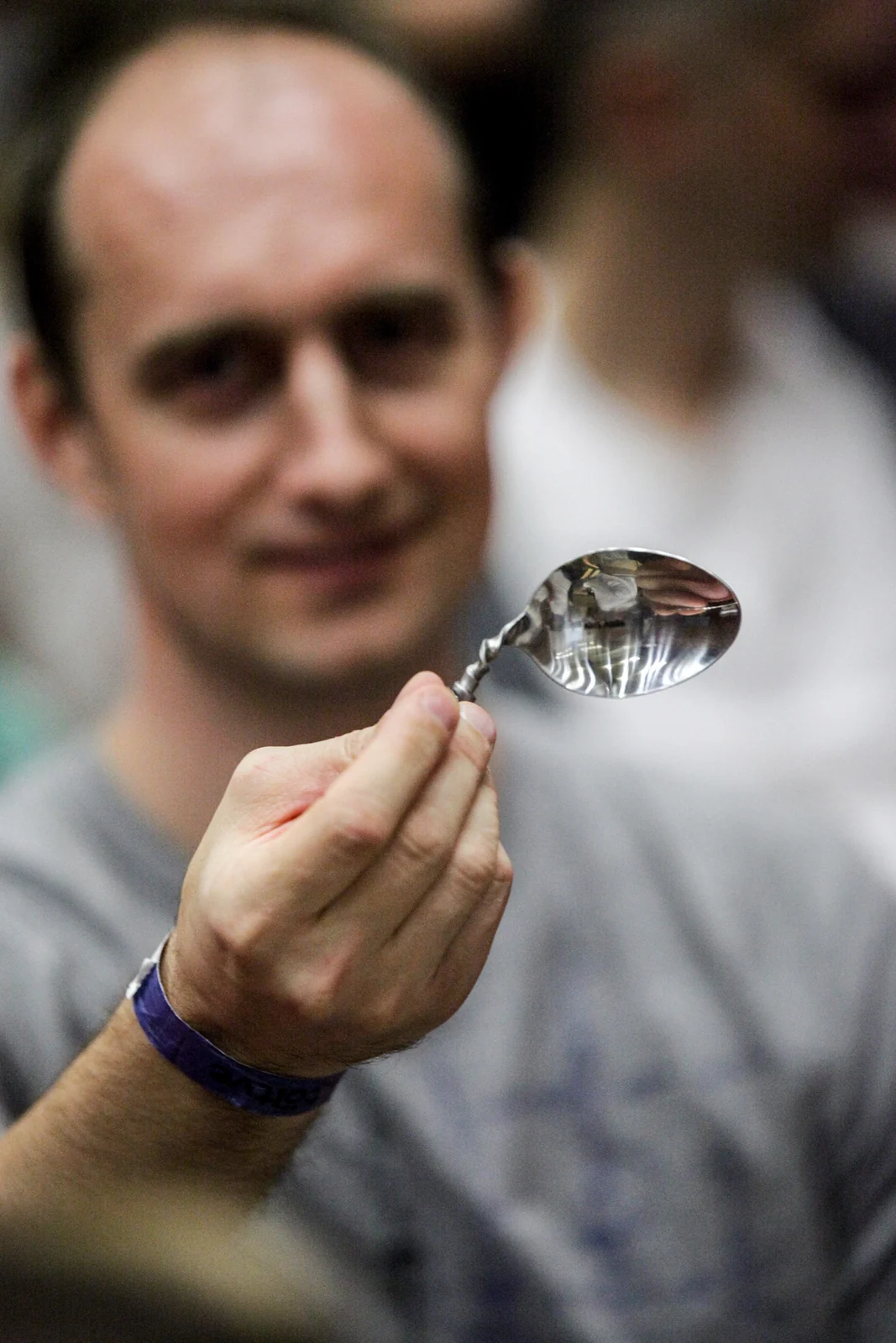A reshaped spoon held before the softly blurred face of its maker