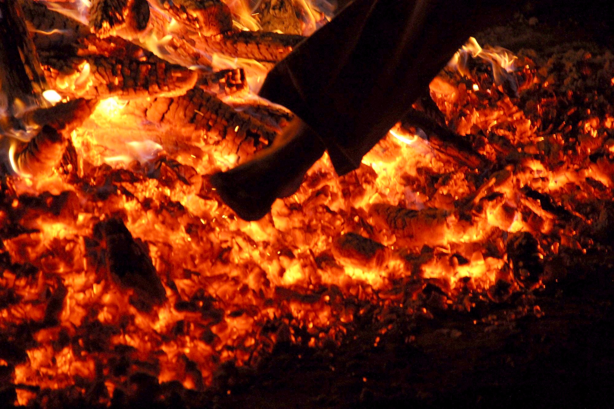 A bare foot moving across a deep bed of glowing coals