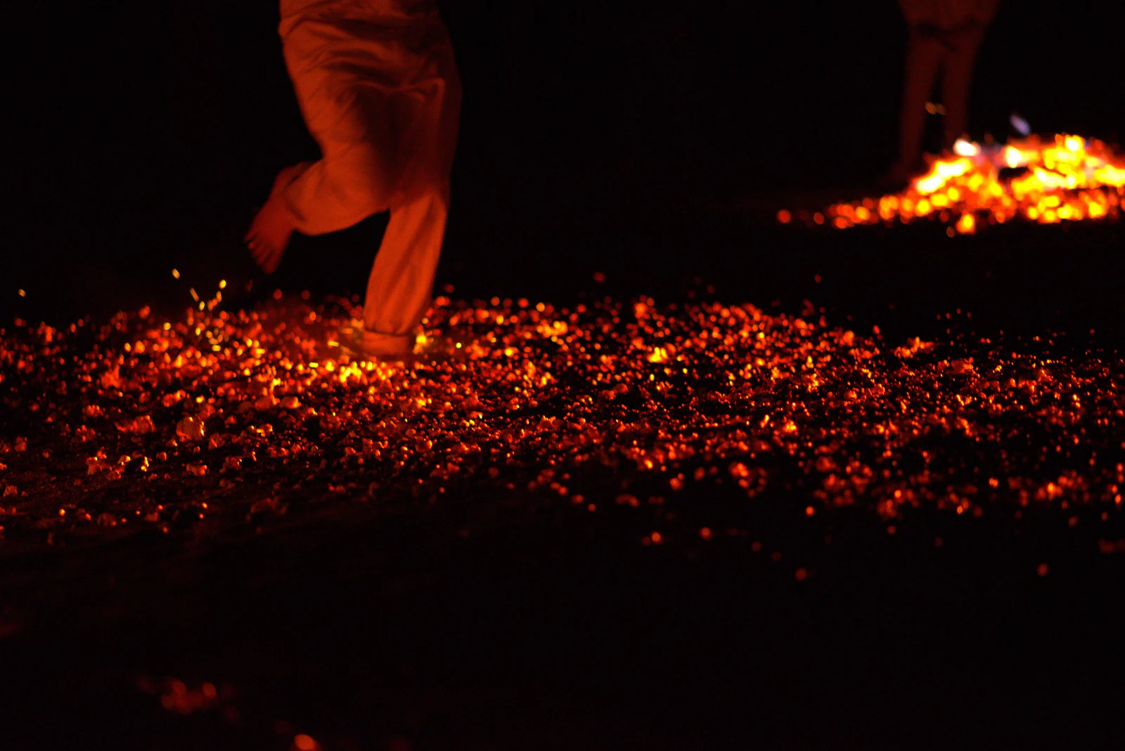 A participant walking barefoot across glowing embers