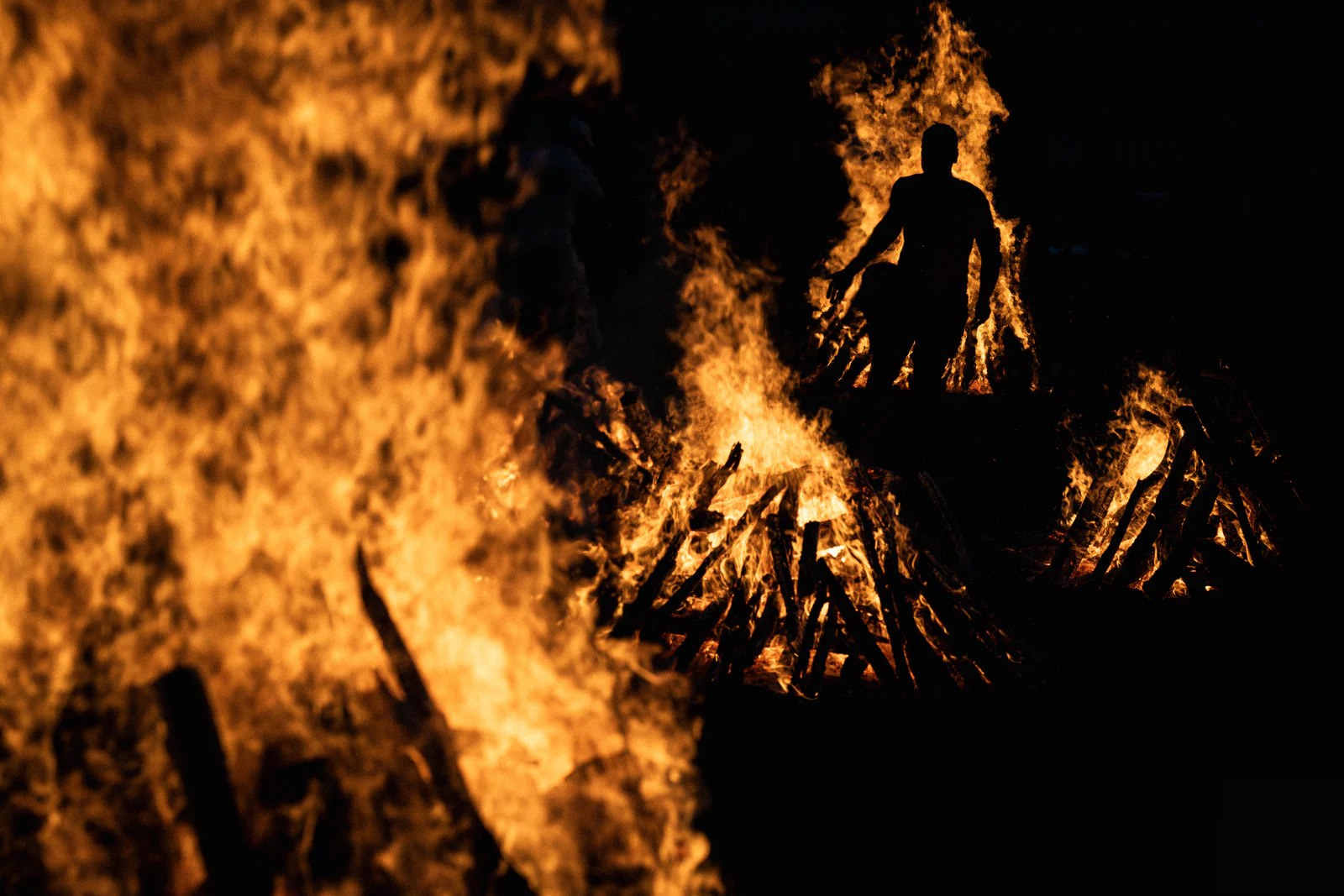 A participant silhouetted between ceremonial fires