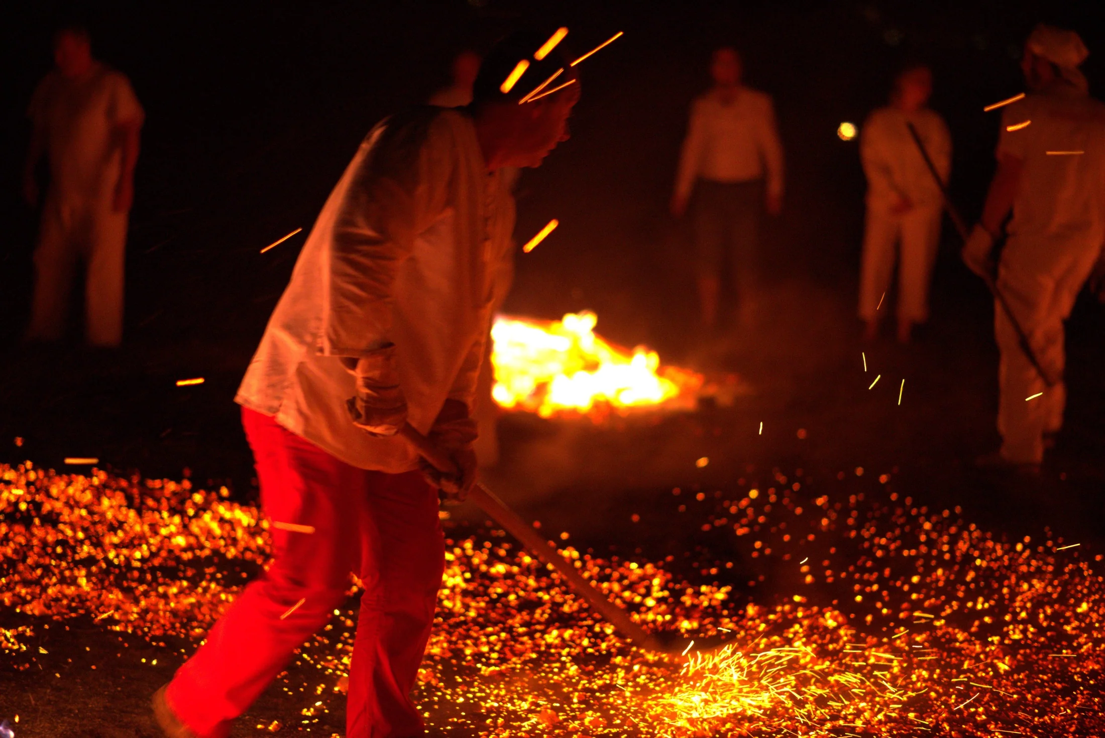 A facilitator preparing a glowing bed of embers