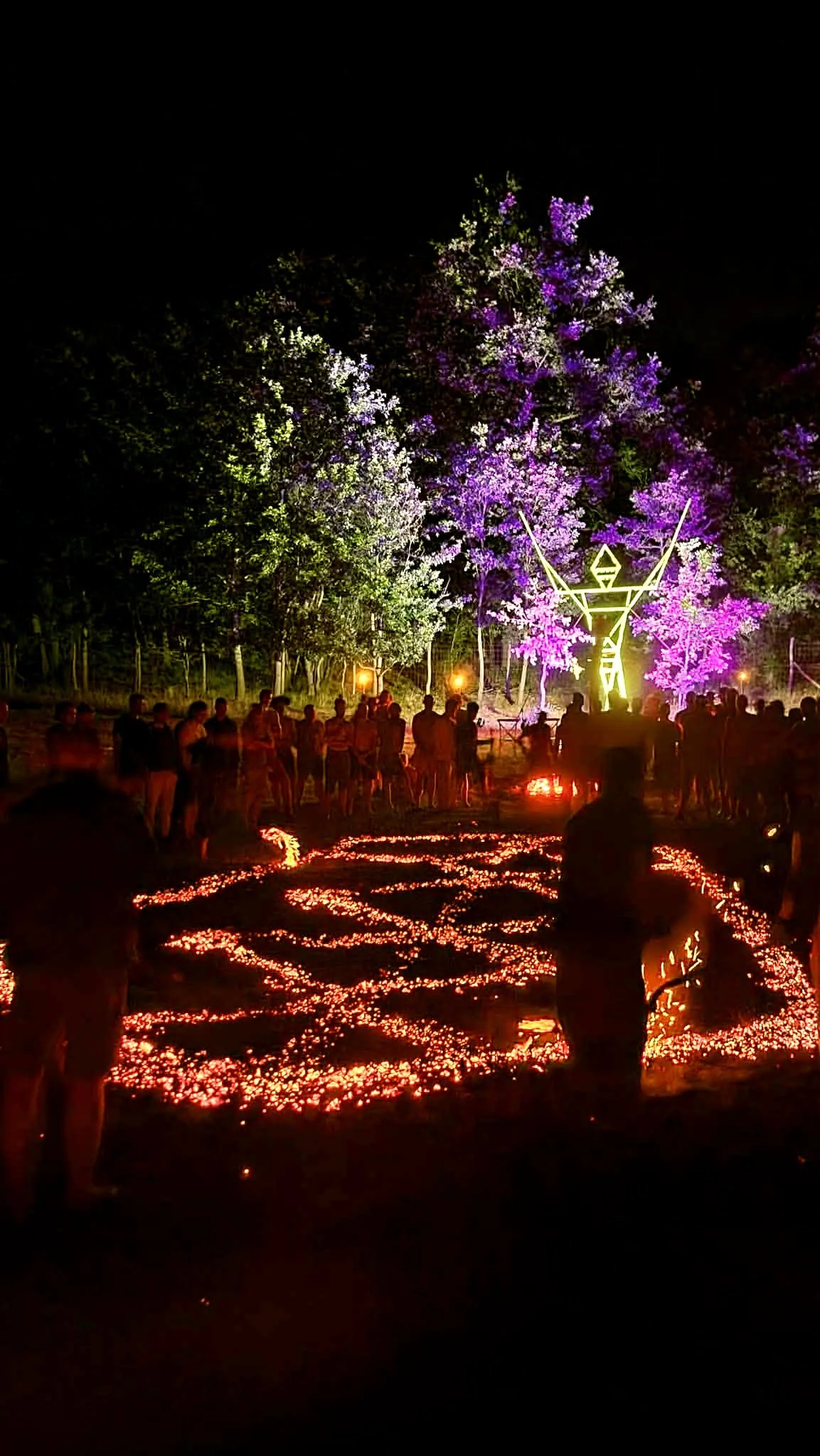 Participants gathered around patterned ember beds at a night-time firewalking event
