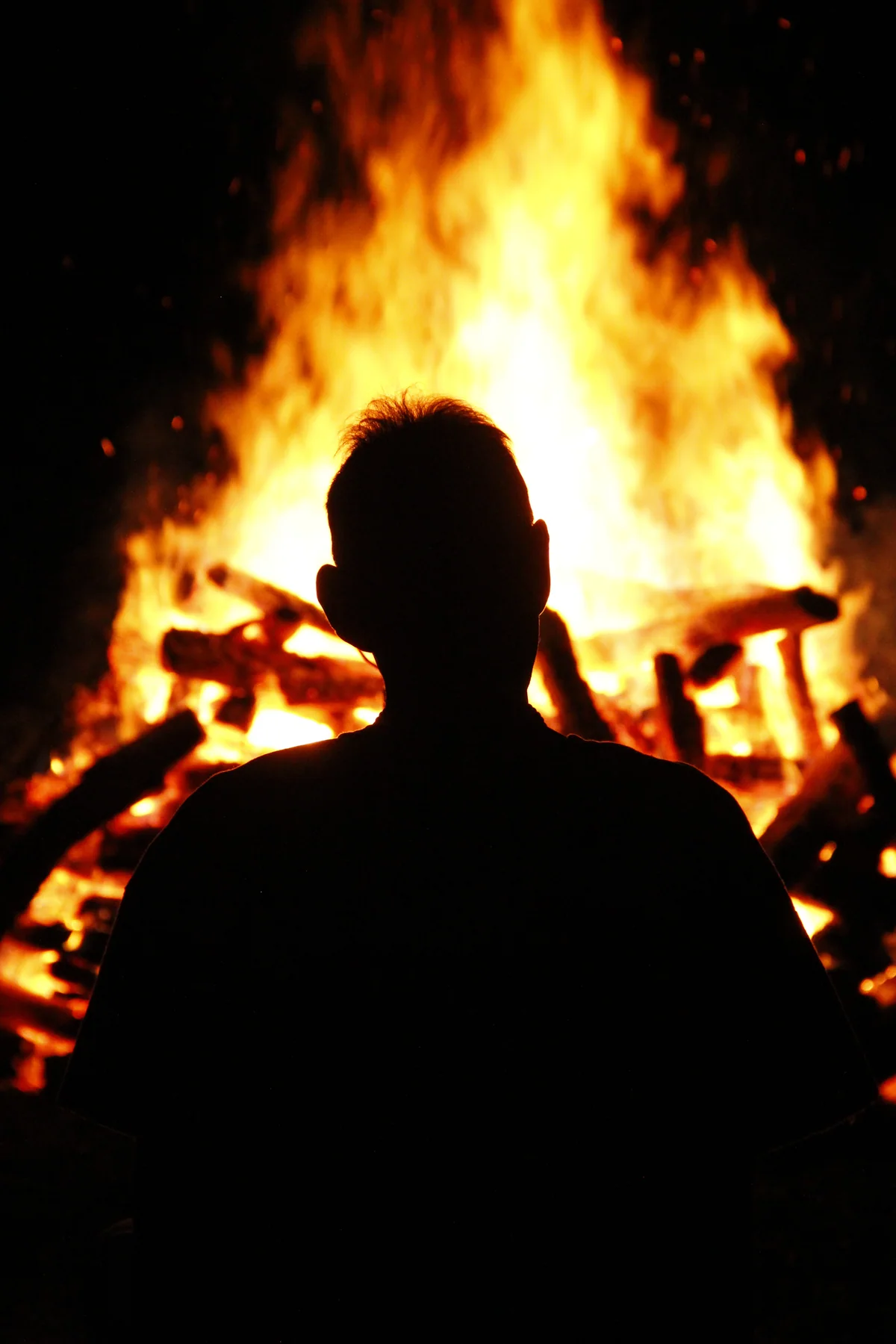 The silhouette of a participant looking into a large fire